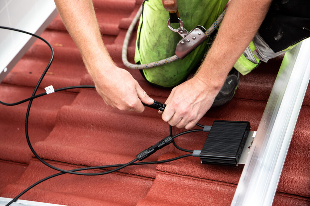 Asentaja liittää sähköjohtoja katolla