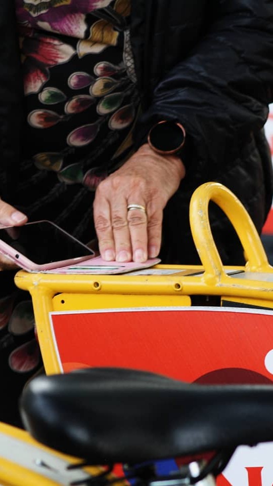 Seniori ottaa kaupunkipyörää käyttöön näyttämällä korttia pyörän laitteelle.