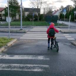 Lapsi taluttaa pyörää suojatien yli