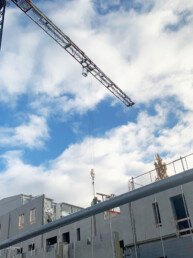 Pilvistä taivasta vasten kuvattu nostokurki ja kerrostalon rakennustyömaata.