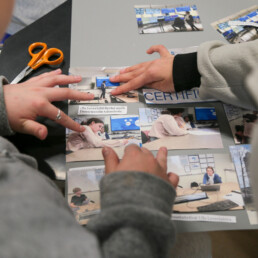 Kaksi oppilasta sommittelemassa valokuvia julisteelle.