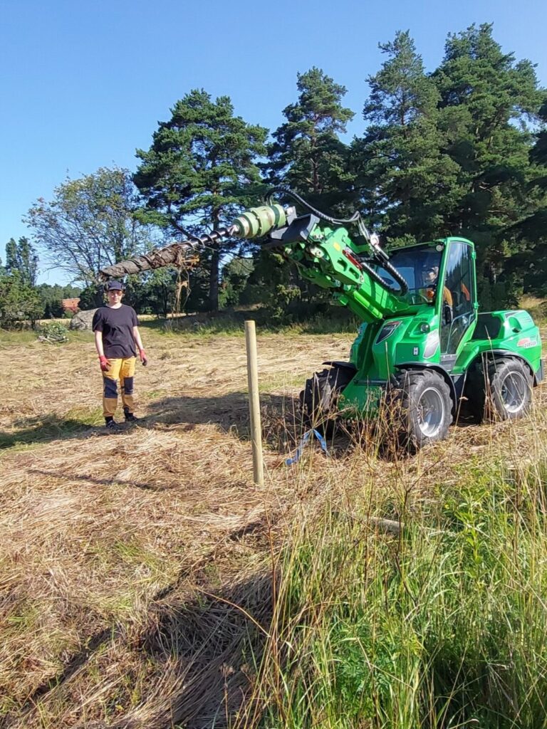 työkone, laiduntolppa, mies seisoo