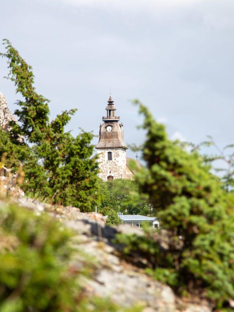 Naantalin kirkon torni etäisyydessä, etualalla katajia