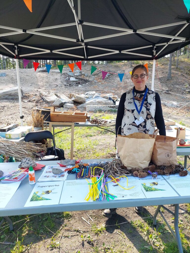 ihminen seisoo pöydän takana katoksessa ja esittelee asioita
