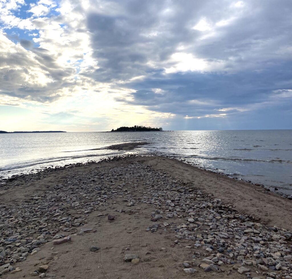 Hiekkasärkkä ja Saaristomaisema ilta-auringossa.