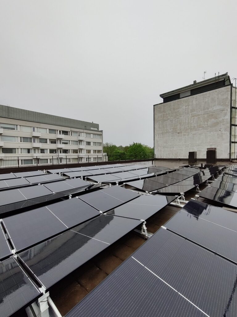 Aurinkopaneeleja katolla, taustalla kerrostaloja.