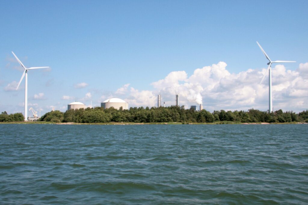 Meri jonka rannalla metsää, tuulimyllyjä ja voimala