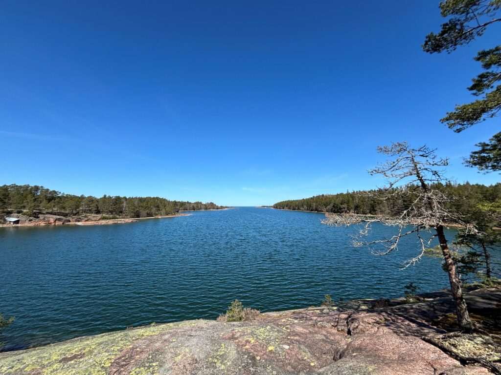 Valokuva, jossa näkymä edessä avautuvalle merelle. Kuva on otettu kalliolta ja edessä näkyy metsäisiä saaria.