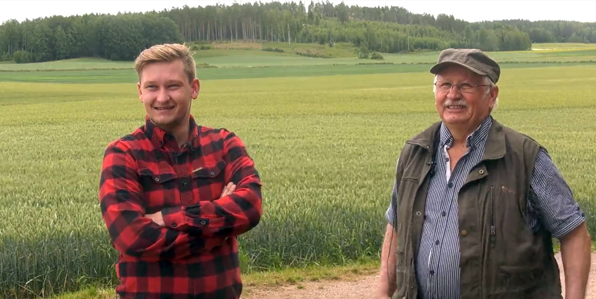 kaksi hymyilevää miestä, taustalla pelto