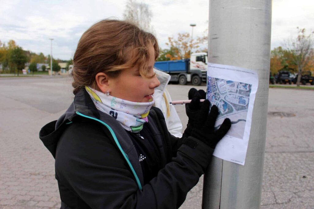 Tyttö kirjoittaa ulkona muistiinpanoja.