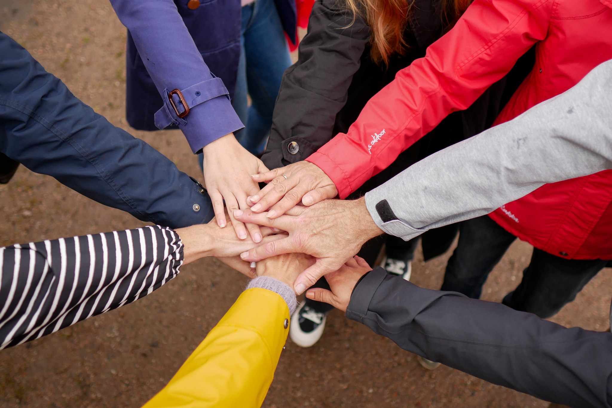 ihmisten käsiä säteittäisessä ympyrässä jossa kämmenet keskellä päällekkäin