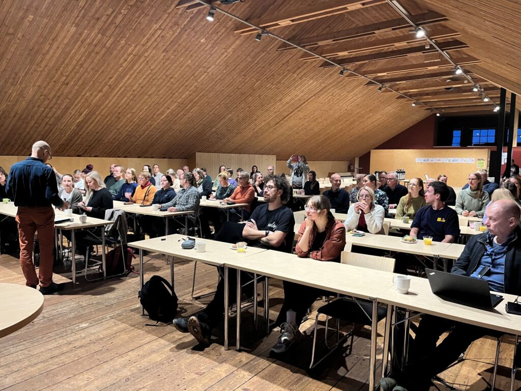 ihmisiä istumassa pöytien takana riveissä