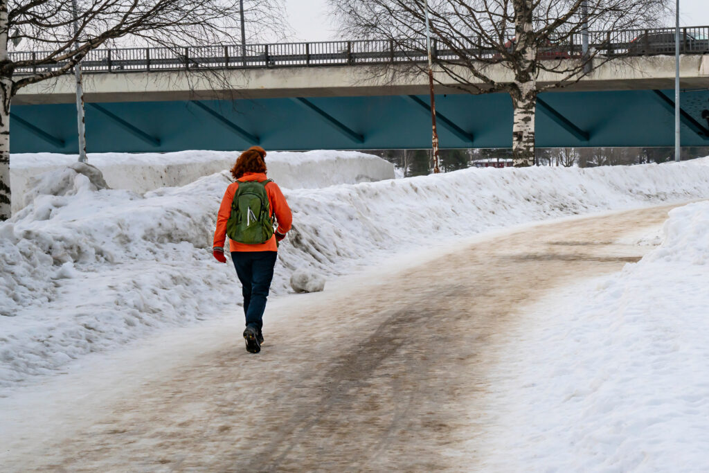 Lumisella tiellä ihminen kävelemässä