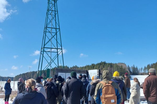 ihmisiä seisoo talvisella pellon laidalla, tuulimylly