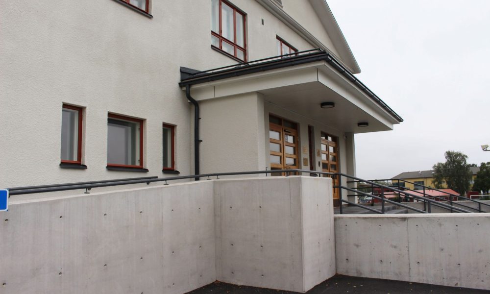 Valkoinen rapattu urheilutalo jonka edessä invaramppi