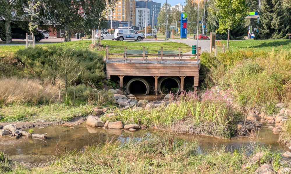 Kaupunkinäkymää, jossa edustalla isot vesiputken päädyt, joiden päällä lavarakennelma.