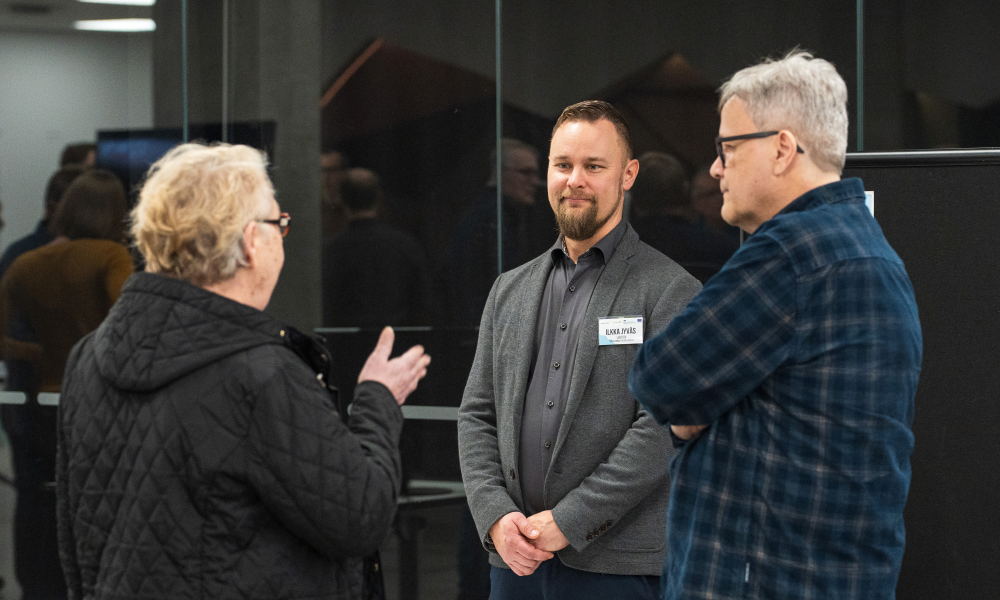 Ikääntynyt nainen selin, kaksi miestä kasvot kuvaan päin